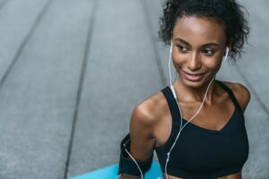 Close up shot of young african woman getting rest while listening music after workout